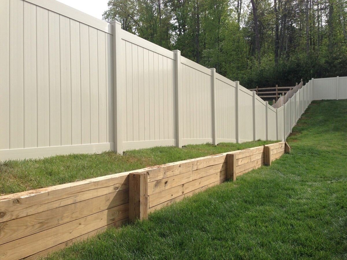 White vinyl privacy fence stepped down a sloped yard